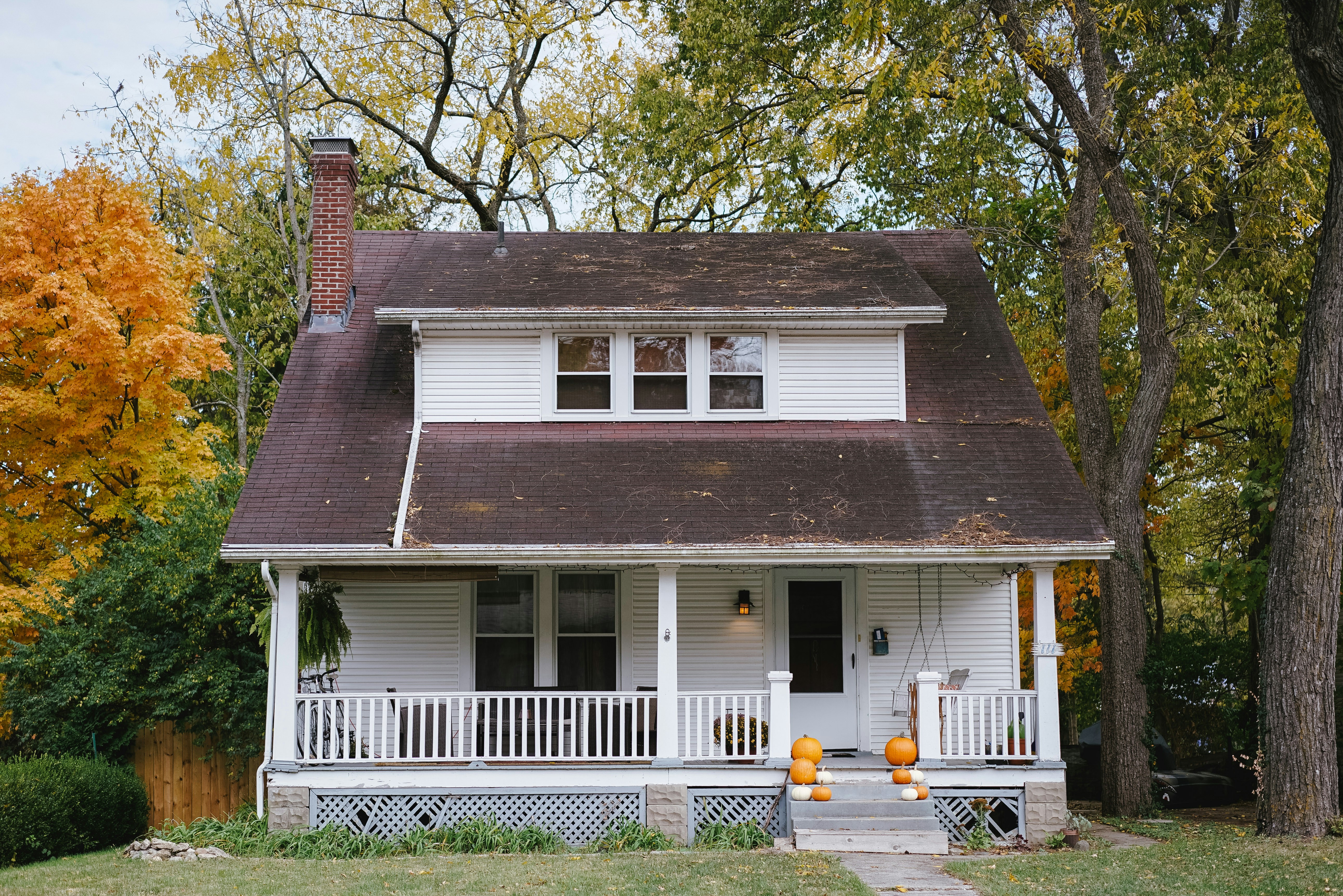 2 story home with pumkins on steps leading up to a porch